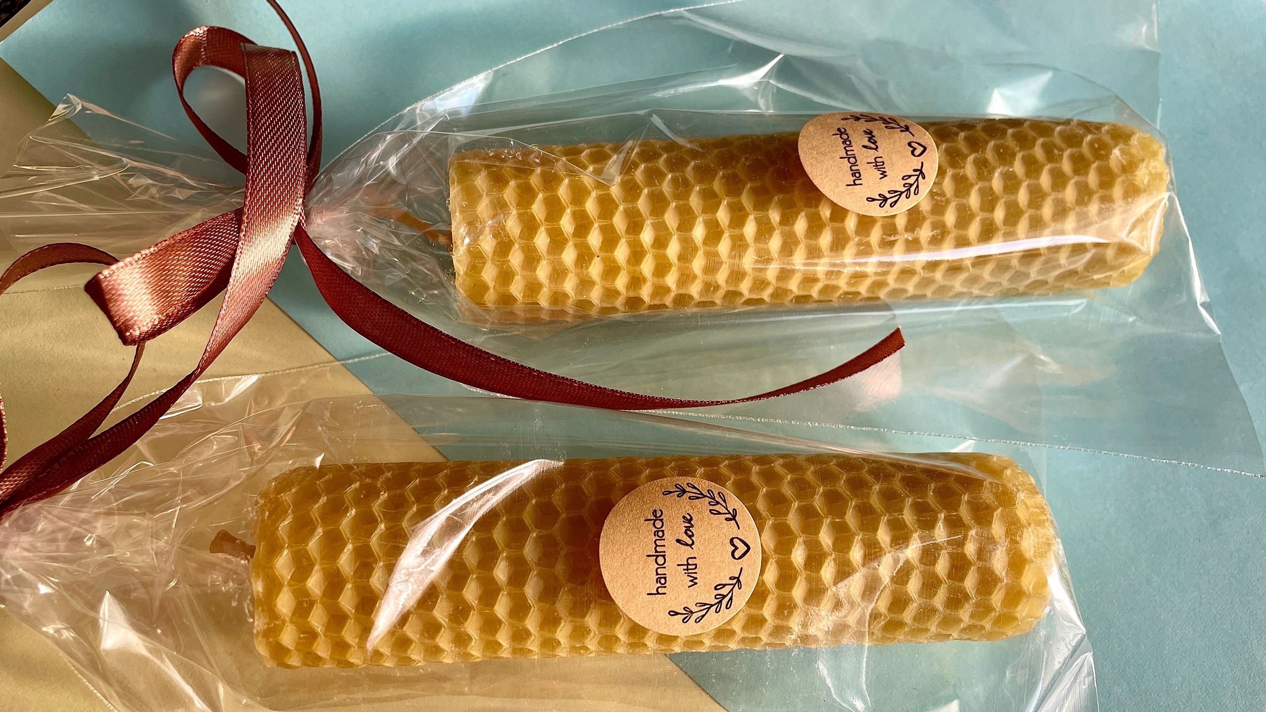 Two handmade beeswax honeycomb candles wrapped with brown ribbons