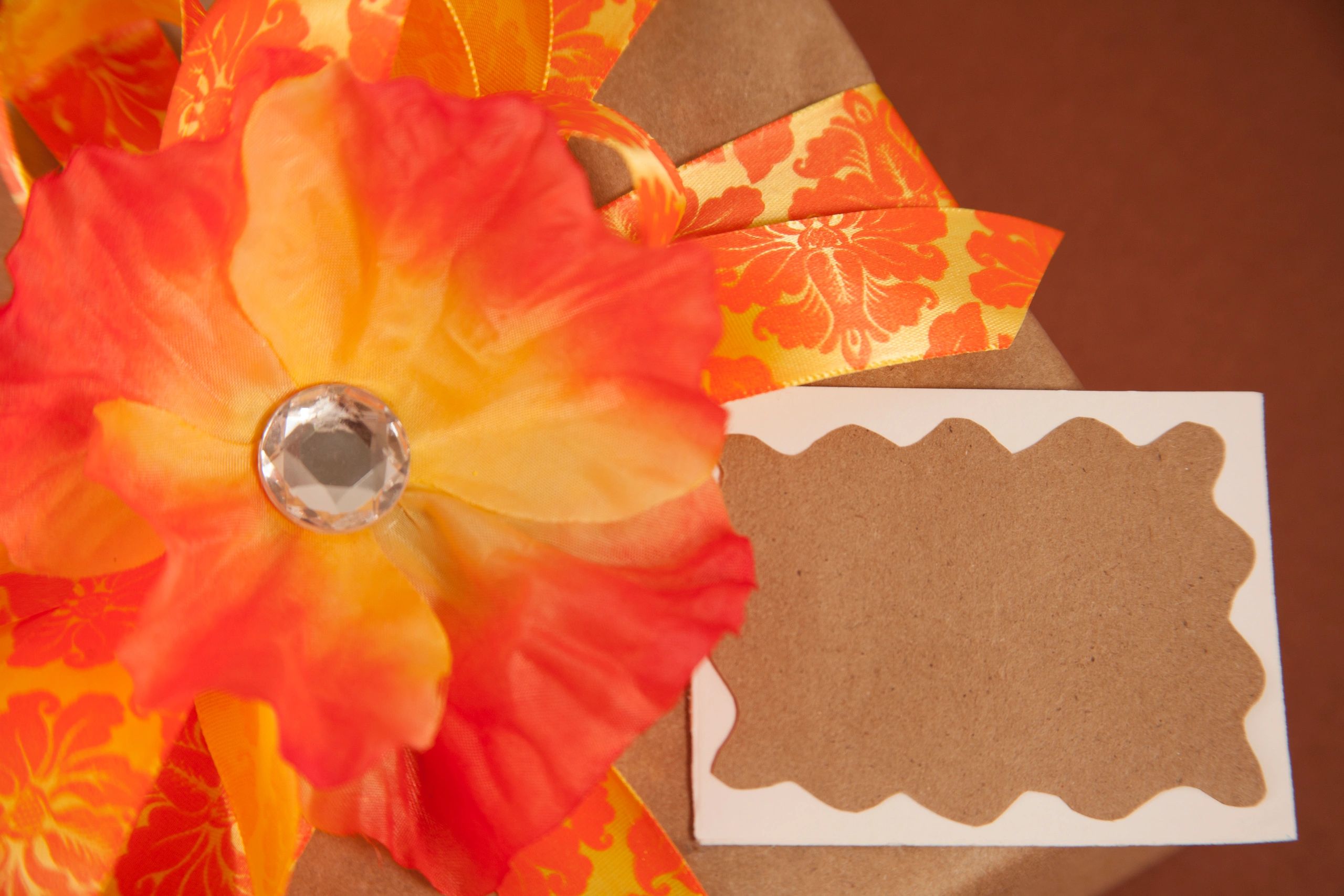 Gift box wrapped in brown paper with orange ribbon and blank card for message
